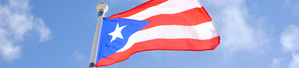 Flag of Puerto Rico Against Blue Sky With Clouds